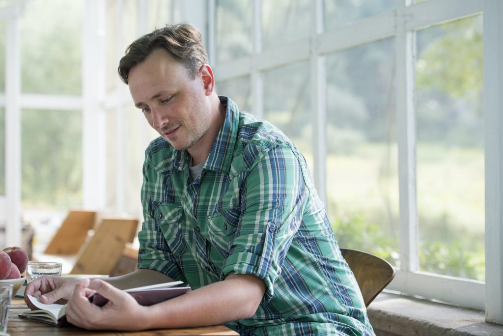 A man sitting at a table reading a book.