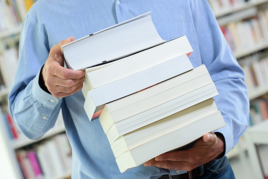 Closeup of stack of books held by man