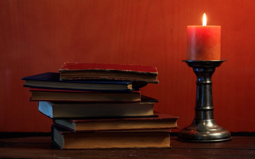 Vintage books and candle on blackboard background